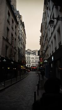 Explore a picturesque cobblestone street in Paris with classic architecture under the evening sky.