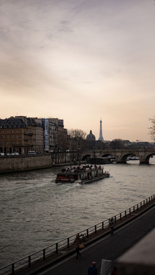 Free Scenic view of Eiffel Tower at sunset with a boat on the Seine River in Paris, France. Stock Photo