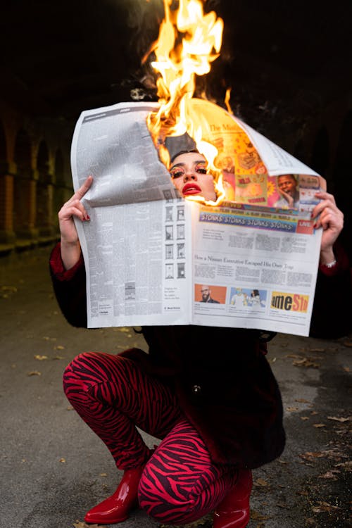 A Woman Holding Newspaper on Fire