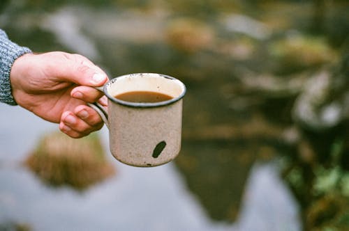 Man Holding a Small Pot with an Instant Soup by a Pond