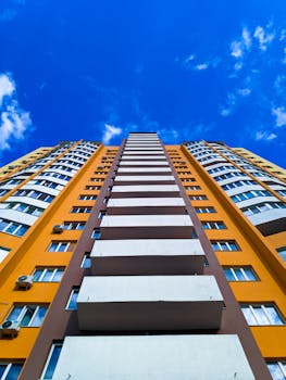 Stunning modern residential building with vibrant yellow facade against a bright blue sky in Ukraine.