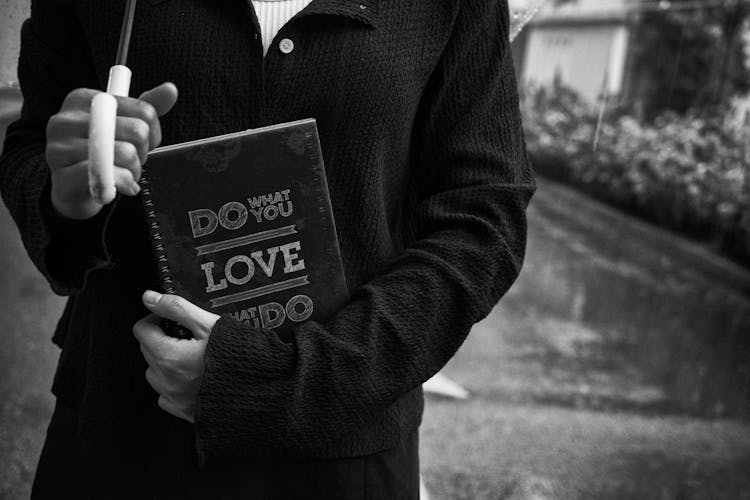 Grayscale Photo Of A Person Holding Notebook