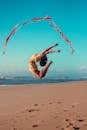 Woman Performing Extreme Gymnastic Exercise with Ribbon on Beach