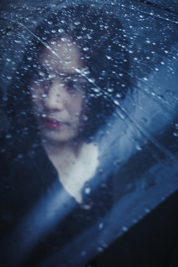 Face Of Brunette Girl Behind Window In Rain