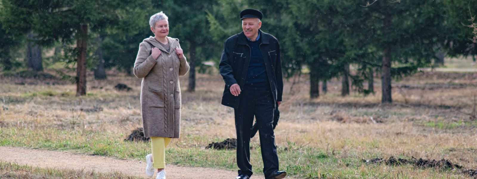 Happy senior couple strolling along a park path on a pleasant spring day.