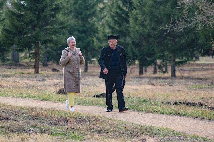 Elderly Man And Woman Walking On Path