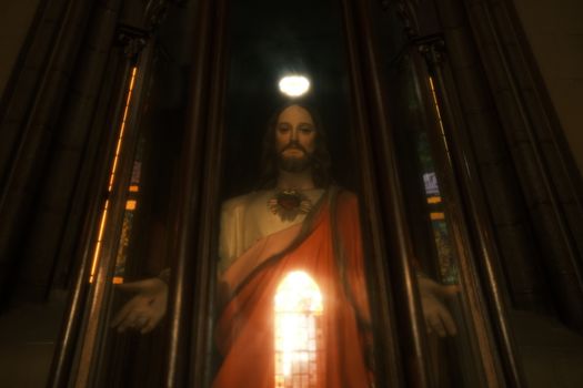 Low angle view of Jesus sculpture behind glass in a dimly lit church.