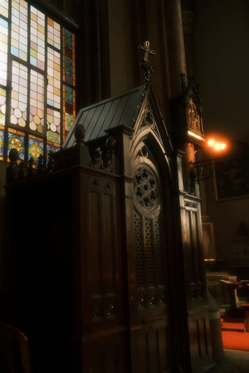 Wooden Confessional and a Stained Glass Window in a Church 