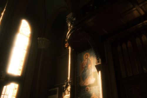 Free Sunlight streaming through stained glass in a church with religious art and iconography. Stock Photo