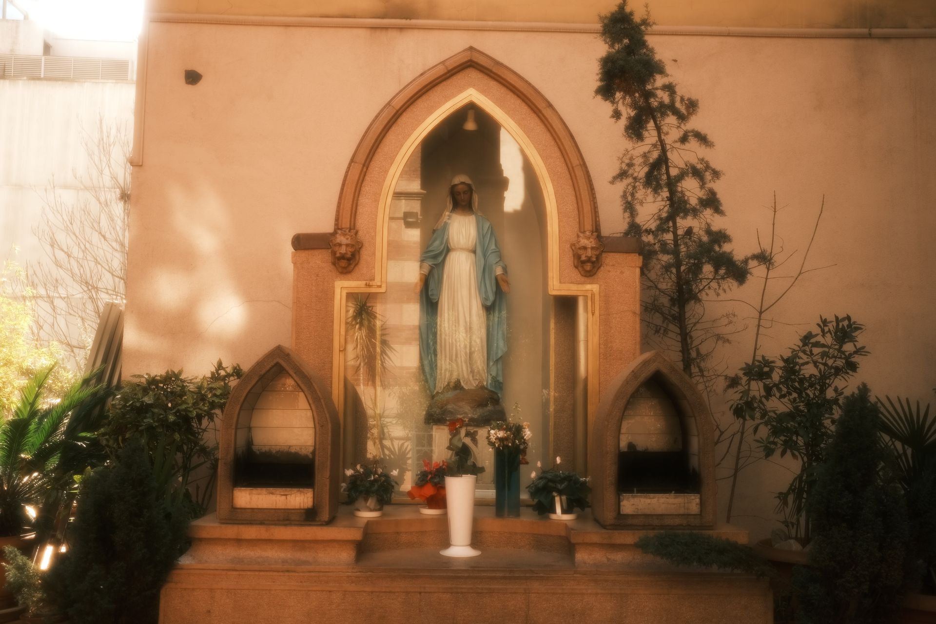 Tranquil outdoor altar with a Virgin Mary statue surrounded by plants.