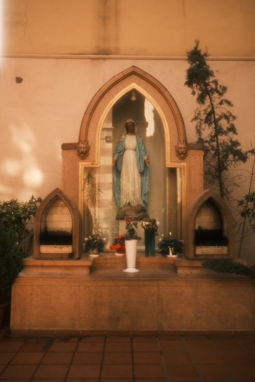 Free Serene shrine with a statue of the Virgin Mary surrounded by plants and candles. Stock Photo