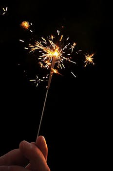 一支手持烟花在漆黑的夜空中闪闪发光，迸发出节日的火花
