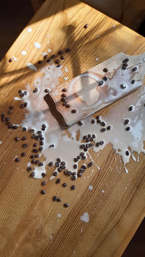 Free High angle view of spilled milk and coffee beans on a rustic wooden table under sunlight. Stock Photo