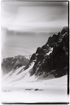 Moody black and white photo of rugged snow-covered mountains in Almaty, Kazakhstan.