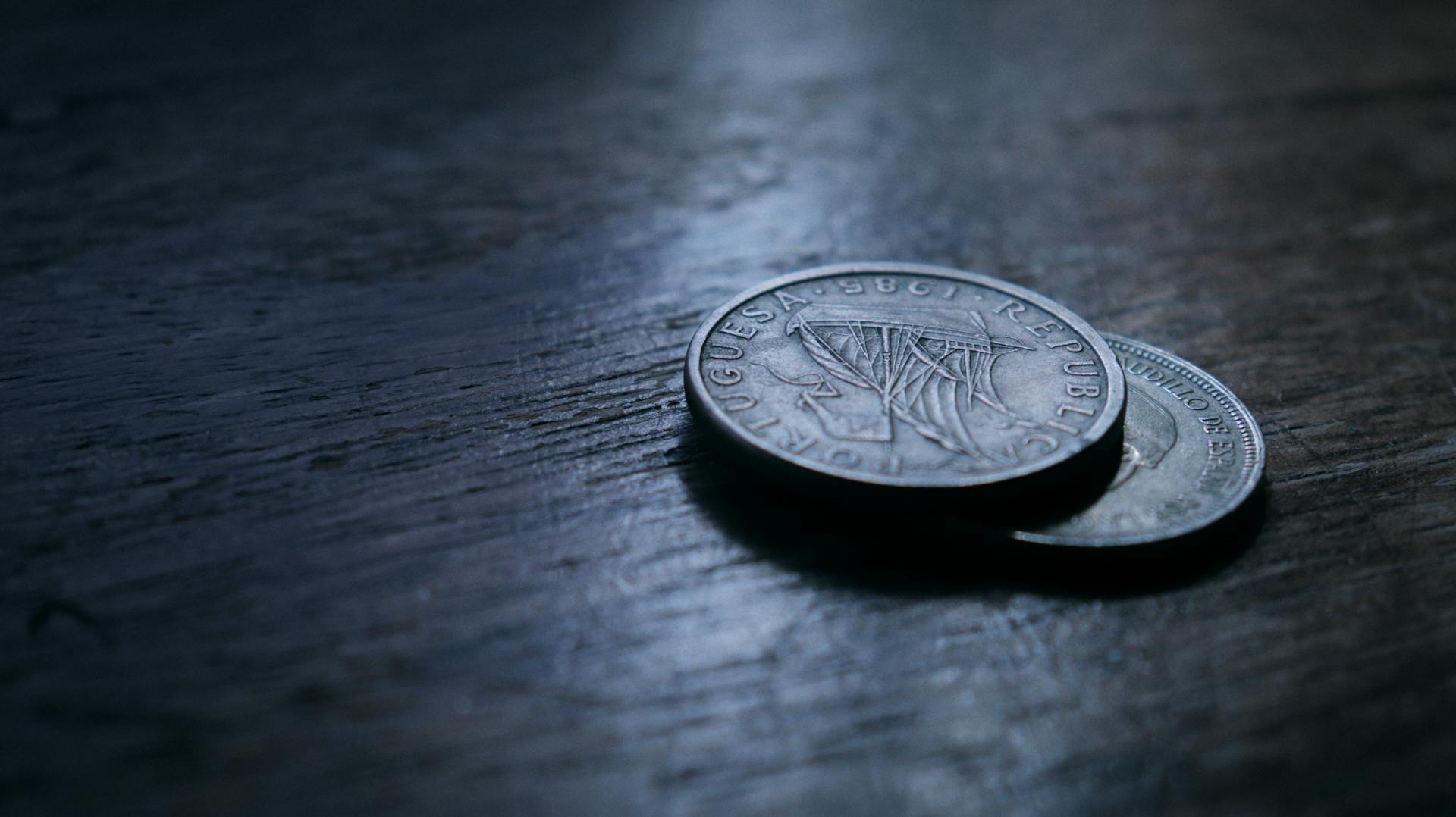 Close-up image of euro coins placed on a textured wooden surface with selective focus.