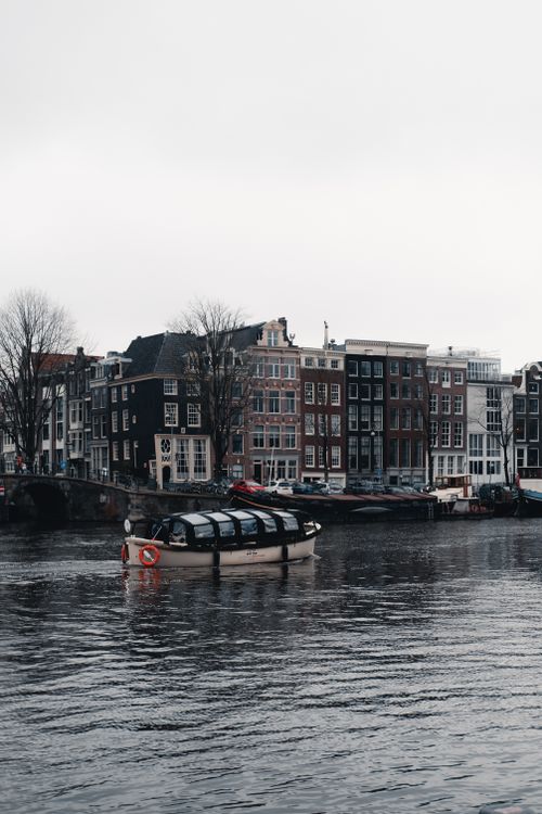 Free Urban landscape of Amsterdam featuring canal and traditional Dutch buildings. Stock Photo