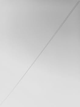 A black and white image featuring minimalist design with power lines against a clear sky.