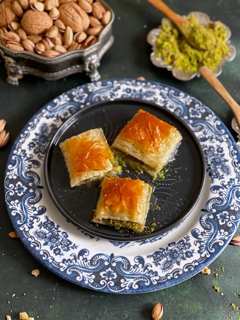 Traditional Turkish baklava with honey and pistachios on a decorative plate, perfect for food photography.