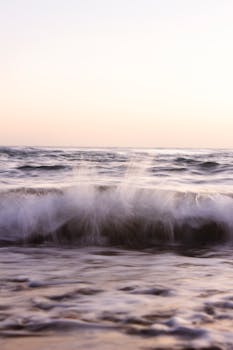 Long exposure of waves crashing against the shore at sunset in Marbella, Spain.
