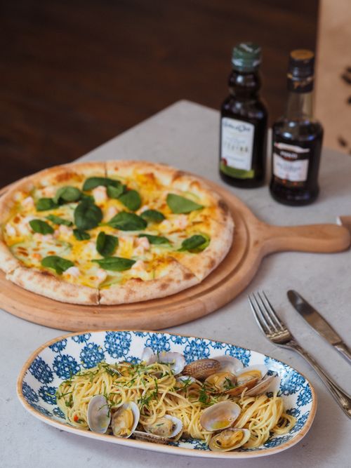 Free Close-up of clam linguine and a fresh pizza with olive oil, perfect for a cozy dinner setting. Stock Photo
