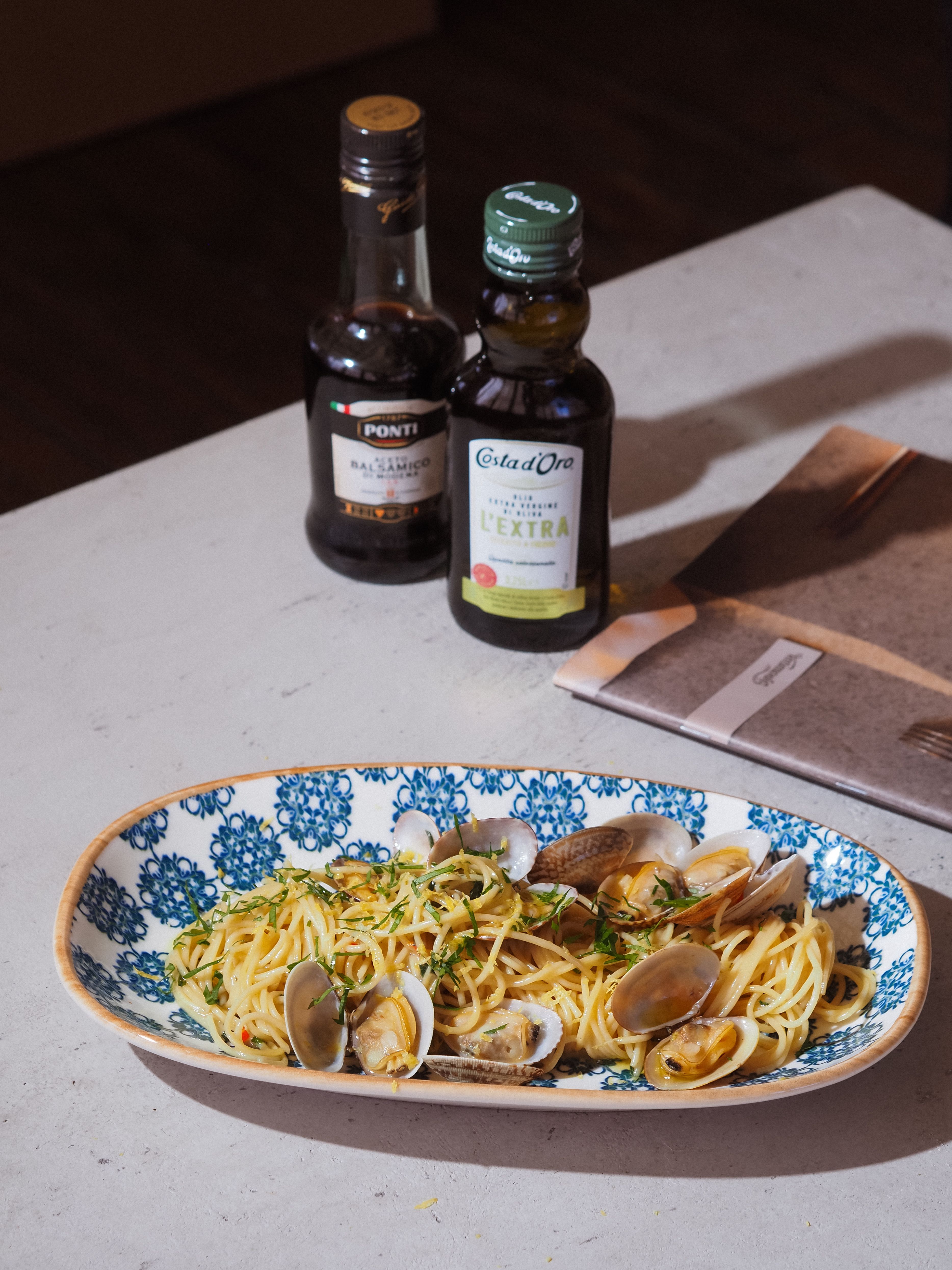 Spaghetti alle vongole serviti in un piatto ovale decorato di blu