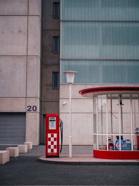 A vintage petrol station beside a modern building in Frankfurt, with retro red and white design.