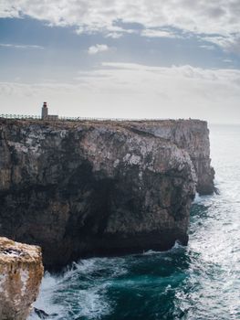 Breathtaking view of Sagres lighthouse perched on a dramatic cliff in Portugal, overlooking the ocean.