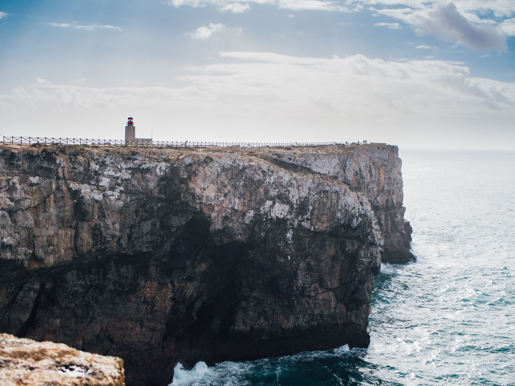 Dramatic cliffside with ocean view and lighthouse in Sagres, Portugal.