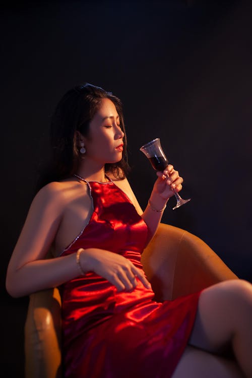 Photo of Woman in Red Dress Holding a Wine Glass