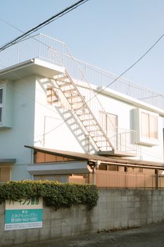 Exterior view of a concrete house with metal stairs under a clear blue sky.