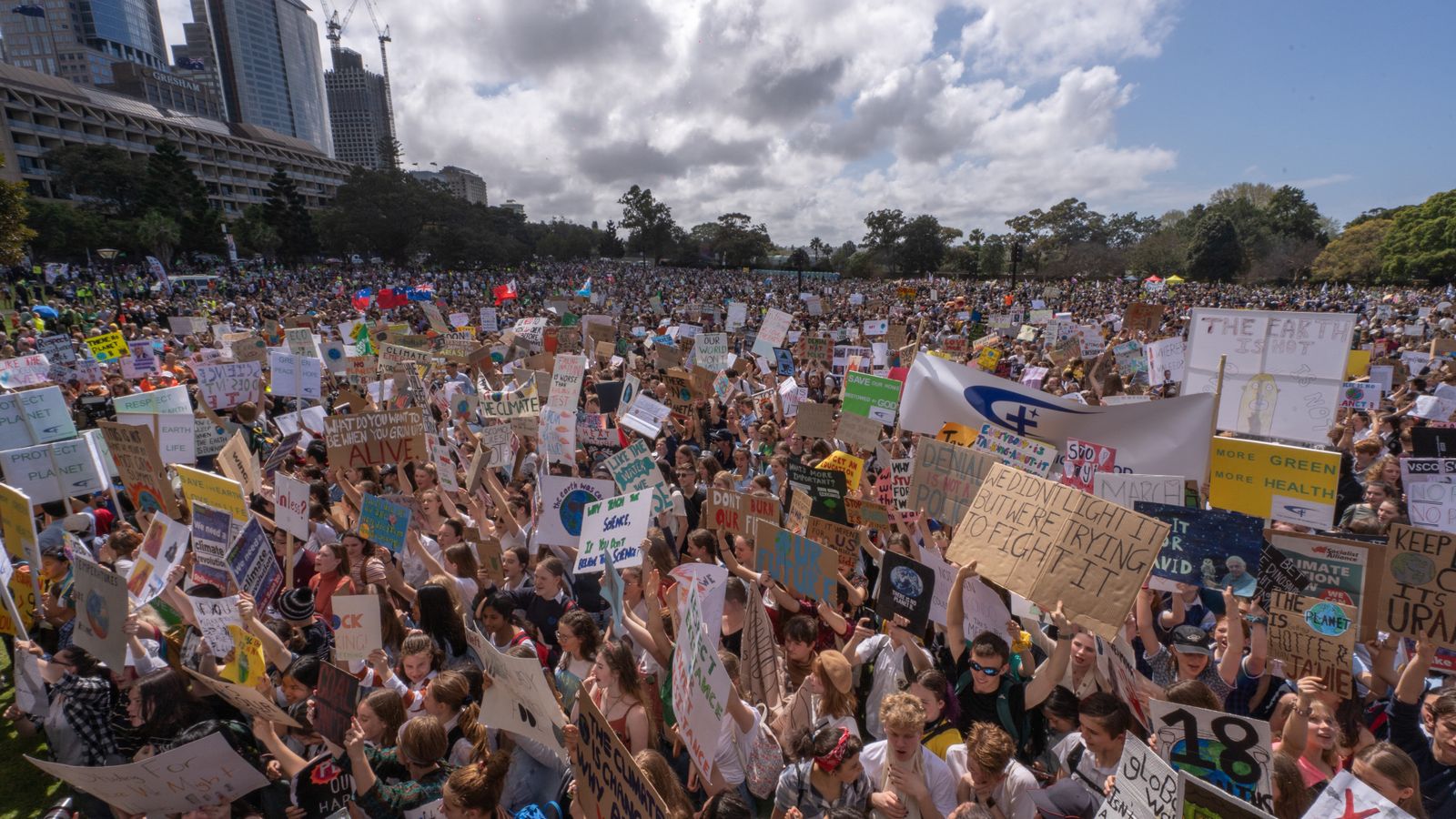 Thousands gather in Sydney's Hyde Park demanding climate action. Diverse crowd with placards.