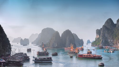 Ships and Boats on Sea Surrounded By Rocky Mountains