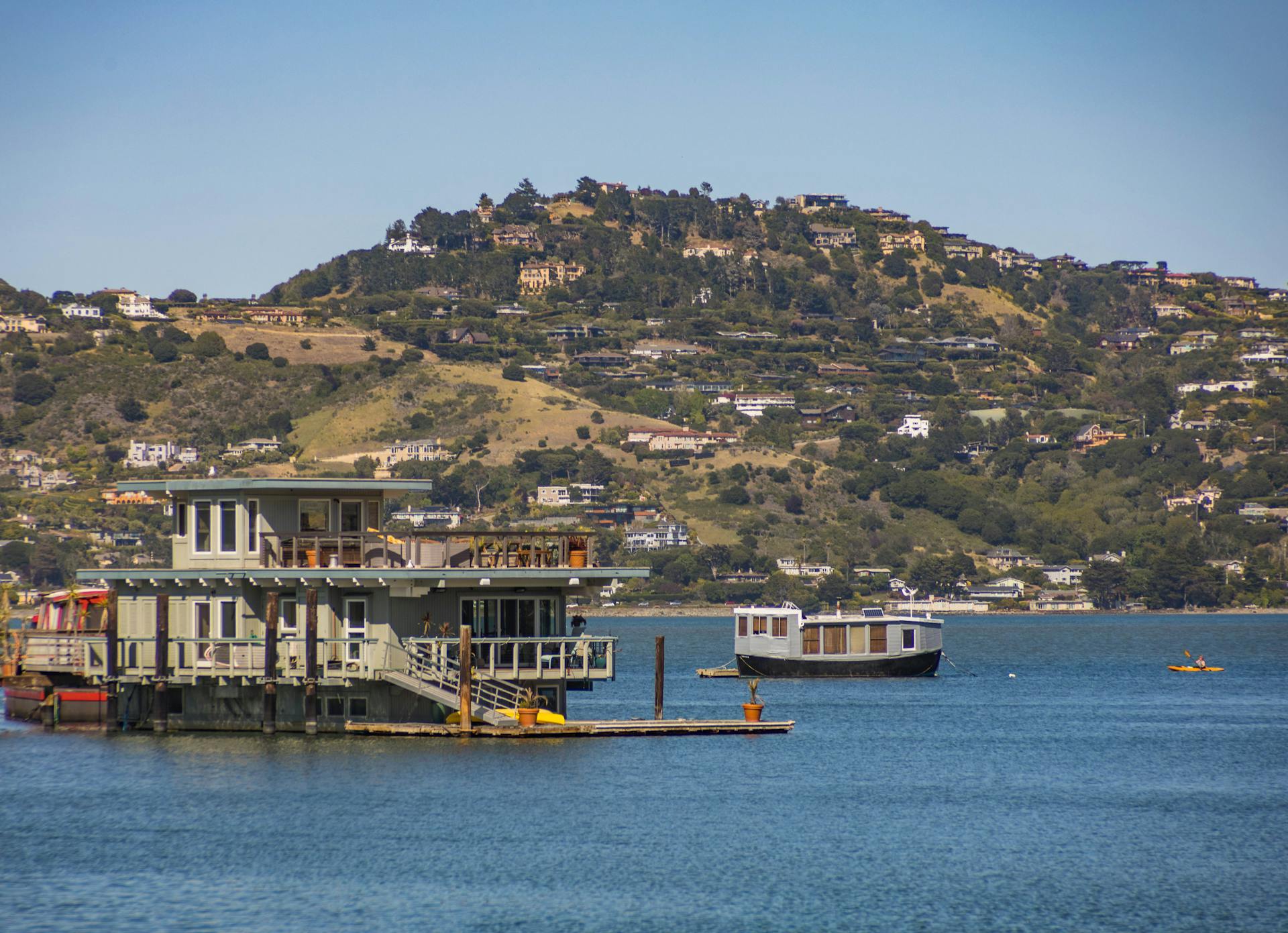 Beautiful floating homes on a serene bay with lush hills in the background.