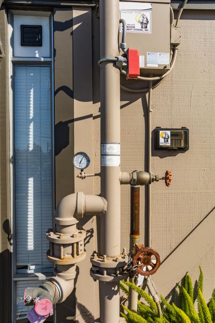 Photo by Robert So on Pexels Close-up of industrial pipes and gauge system on an exterior building wall.