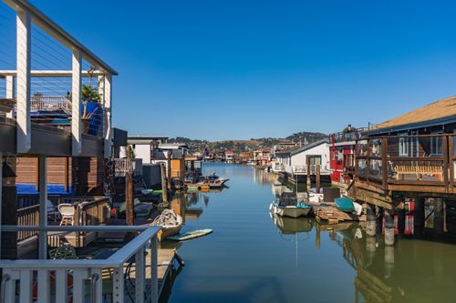 Free Peaceful canal with floating houses and boats under clear sky. Stock Photo