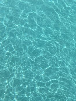 Clear blue water reflecting sunlight in a serene swimming pool, creating a calming effect.