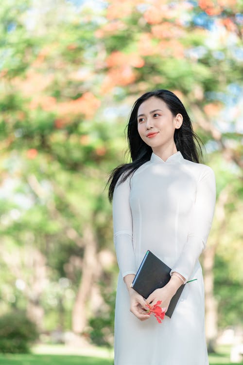 Free A Woman in an Ao Dai Holding a Journal Stock Photo