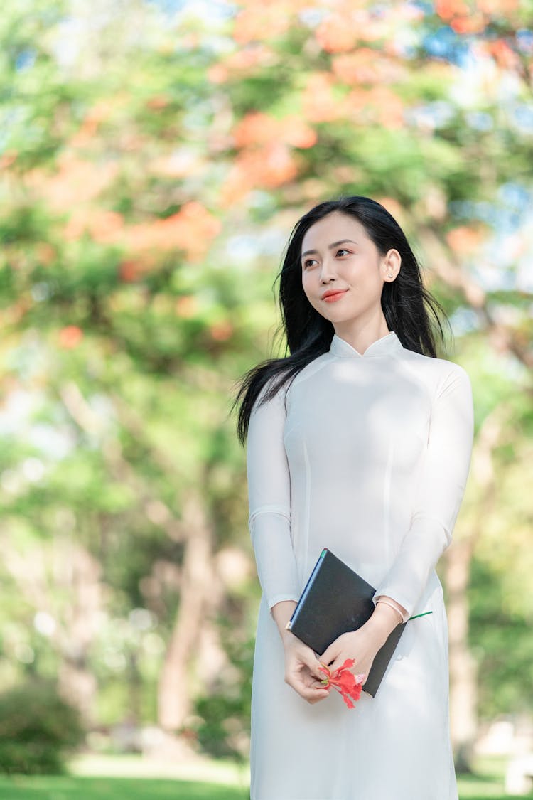 A Woman In An Ao Dai Holding A Journal