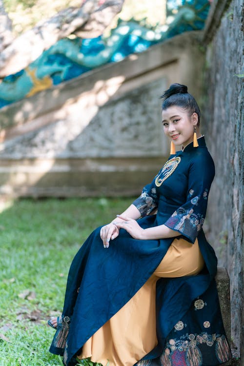 Woman in Blue Traditional Dress Sitting on Concrete