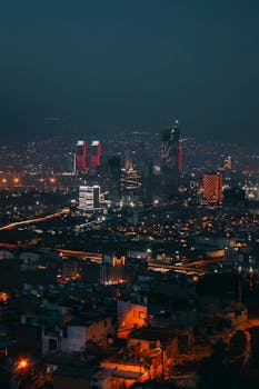 Stunning nighttime aerial view of İzmir's modern cityscape featuring illuminated skyscrapers.