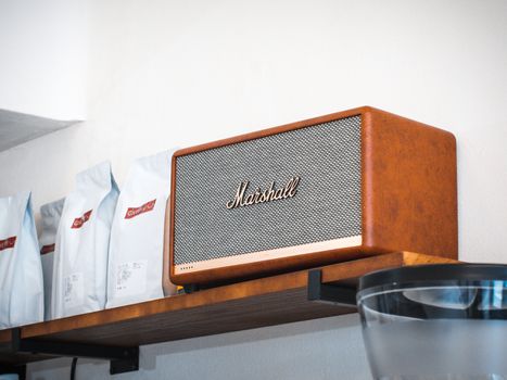 Stylish Marshall speaker showcased on a wooden shelf inside a modern café environment.