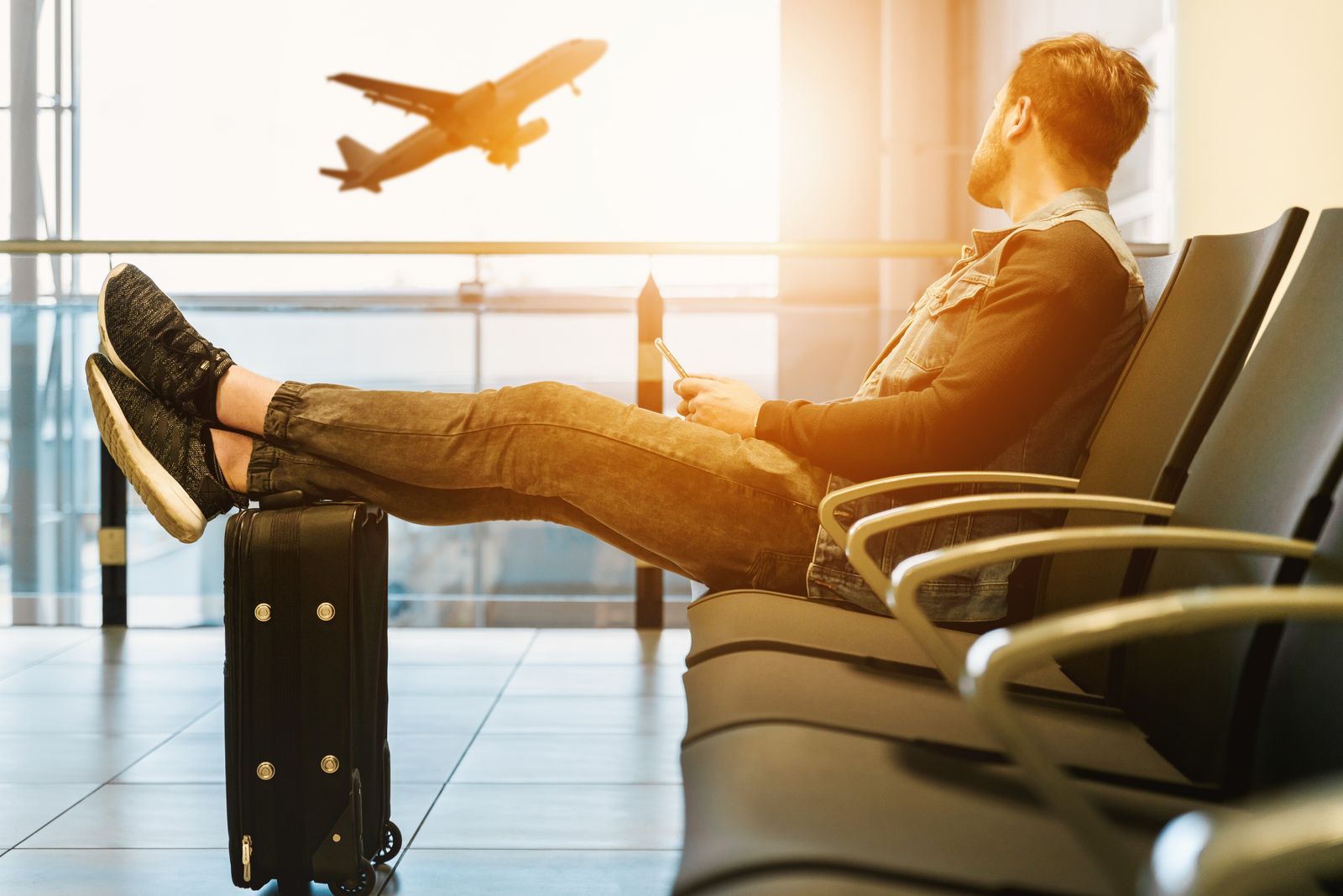 Male traveller seated in an airport with lower legs and shoes visible for men’s travel compression sock selection. Photo: Pexels.