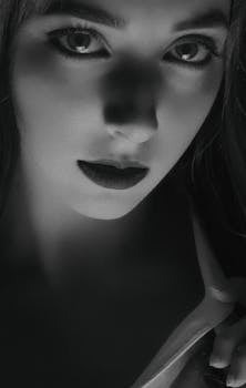 这幅迷人的黑白特写肖像描绘了一位眼神深邃、光影效果极具戏剧性的女性