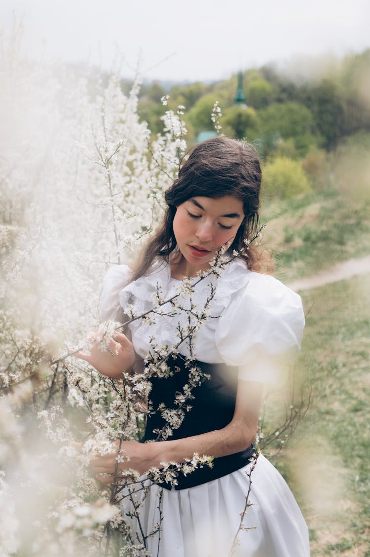 Young Woman In A Dress Next To Trees In Spring