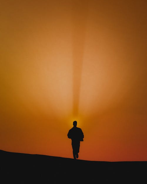 Free Silhouette of Man Standing on Hill during Sunset Stock Photo
