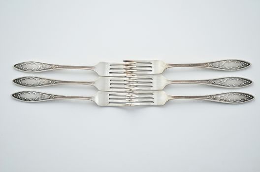 Four intricately designed silver forks arranged on a white surface, showcasing elegant cutlery.