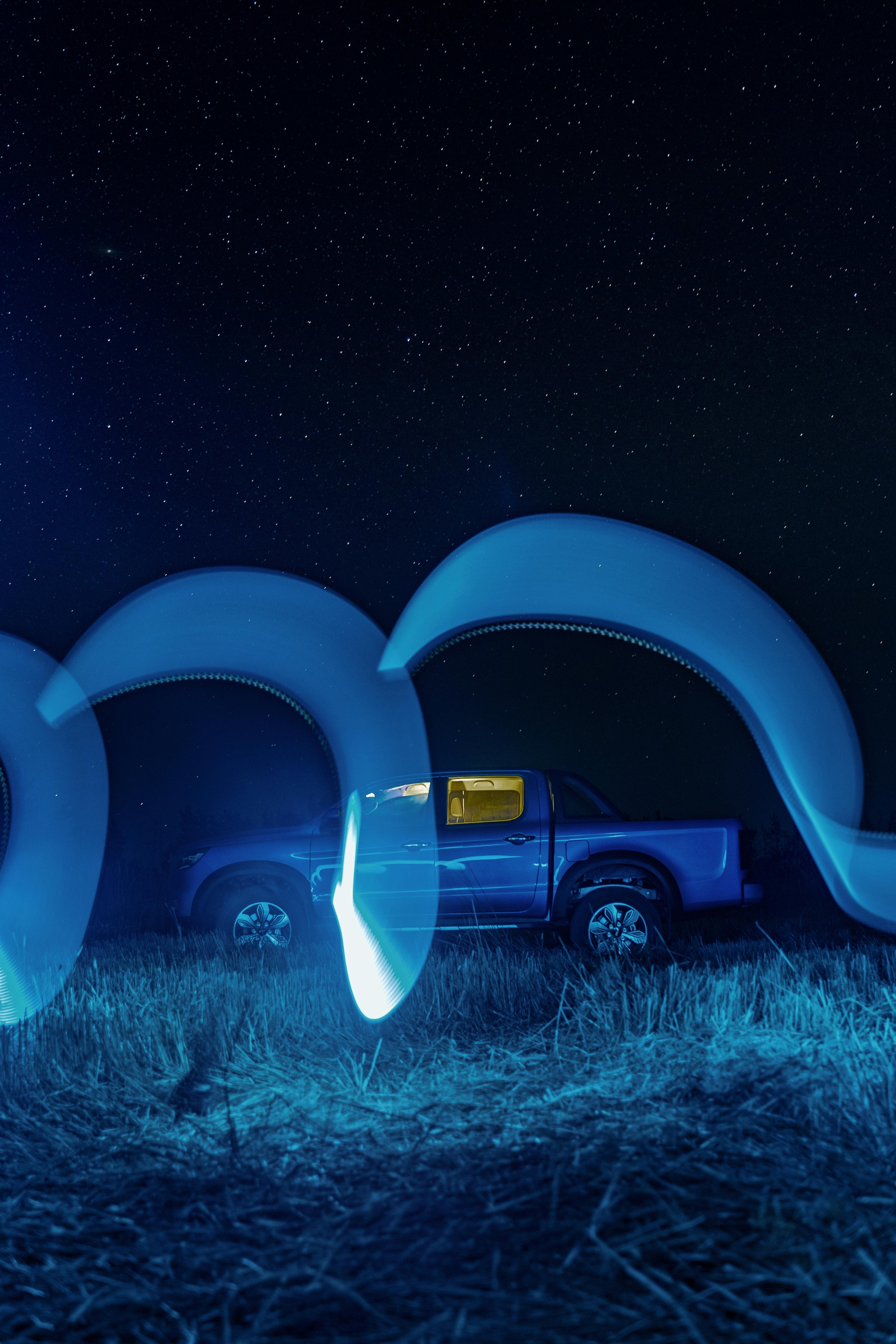 Blue truck under starry night sky with creative light painting.