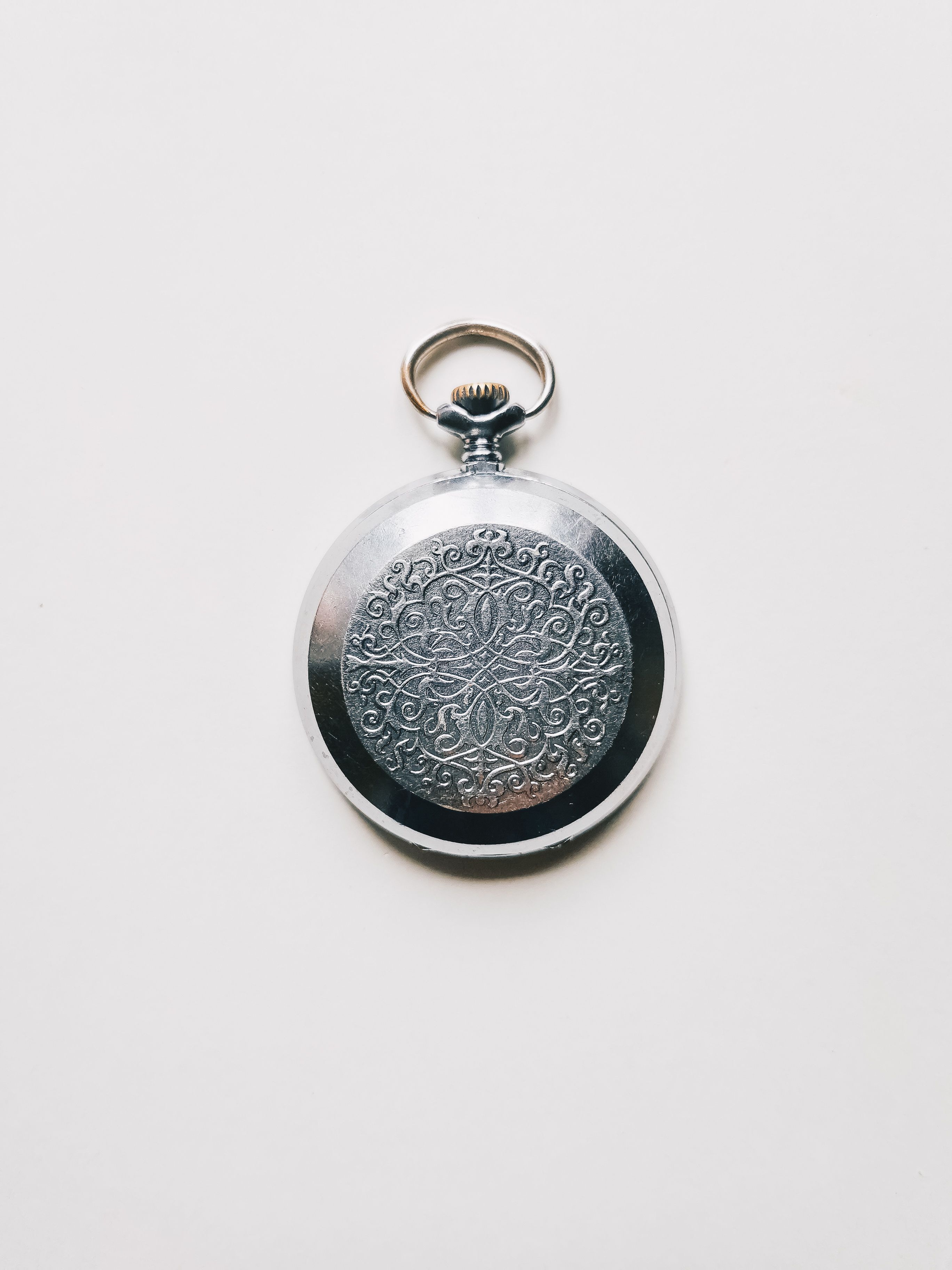 A beautifully crafted silver pocket watch on a white background.