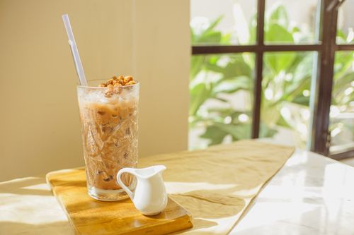 Free Close-up of delicious iced coffee on a wooden board with a pitcher, set indoors with natural light. Stock Photo