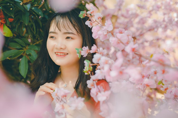 Portrait Of A Smiling Teenager Girl Into Flowers